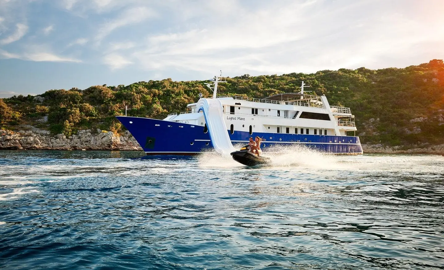 Blue and white luxury Lupus Mare yacht anchored near shore, calm blue water