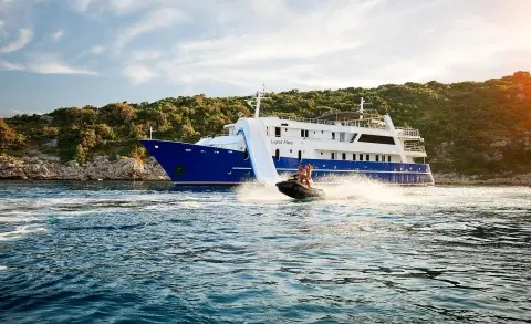 Blue and white luxury Lupus Mare yacht anchored near shore, calm blue water