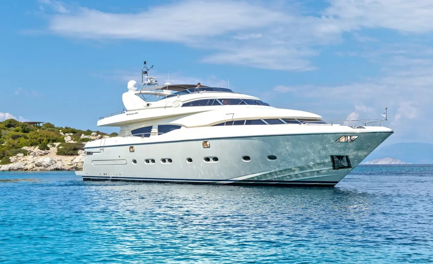 Luxurious white yacht named Divine anchored on clear blue water with blue sky