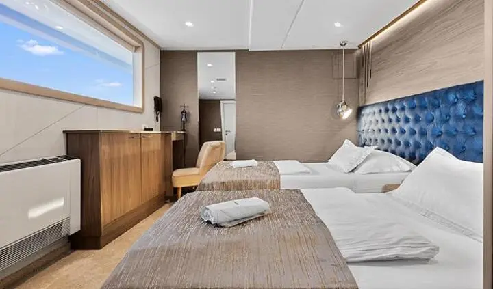 Bella yacht cabin with double bed, beige bedding, and window seating area