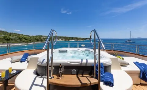 Yacht Queen Eleganza aft deck with entry stairs, hot tub, blue water backdrop