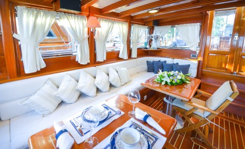 Interior view with white upholstery along dark wood walls, a wooden table, and white curtains
