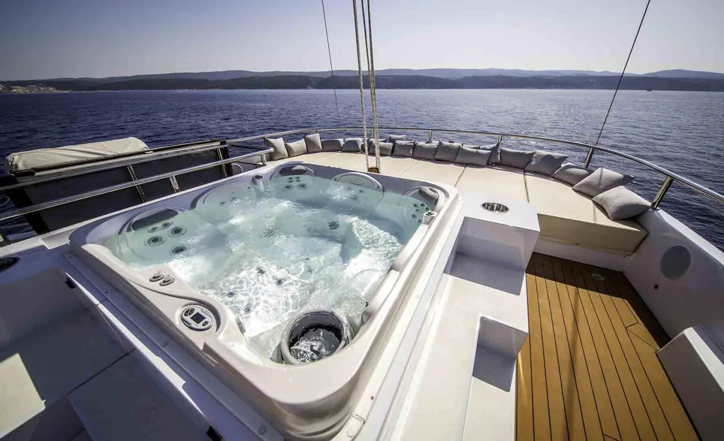Omnia yacht hot tub on deck with blue water view and wooden trim