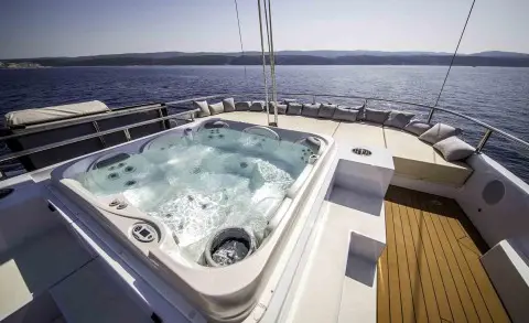 Omnia yacht hot tub on deck with blue water view and wooden trim