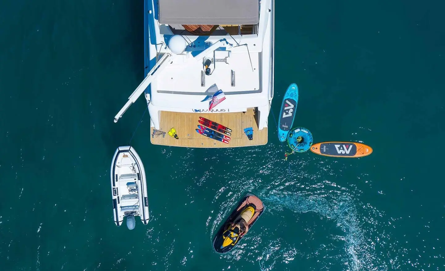 Aerial view of Quo Vadis I yacht at anchor with crew onboard and small boats nearby