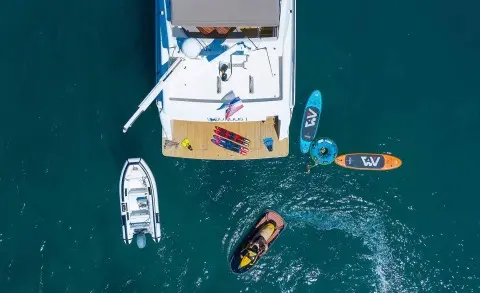 Aerial view of Quo Vadis I yacht at anchor with crew onboard and small boats nearby