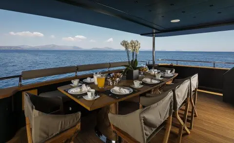 Elegant yacht dining setup on deck at sunset with tableware and chairs
