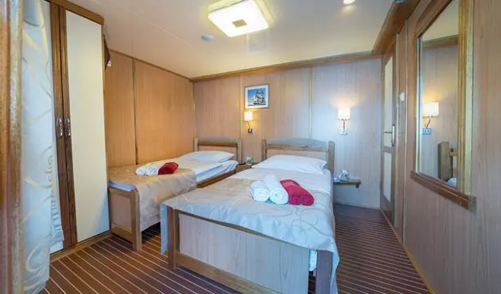 Twin cabin aboard Barbara yacht with two single beds and wood paneling