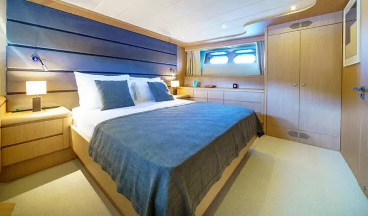 Phantom yacht cabin with king bed, blue bedding, and window-lit ensuite area