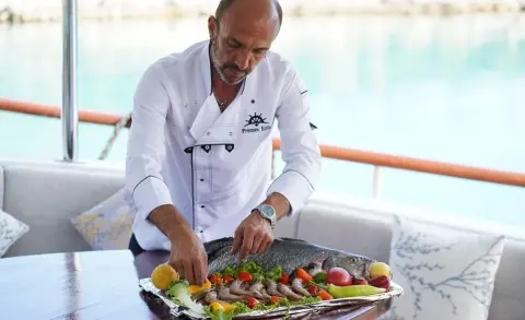 Prenses Esila yacht on calm sea with sunset glow and guests dining onboard