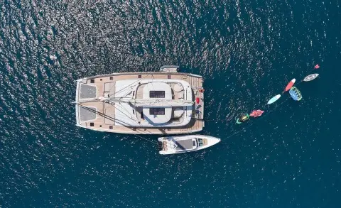 Aerial view of a gulet named Genny with white deck anchored near a small boat
