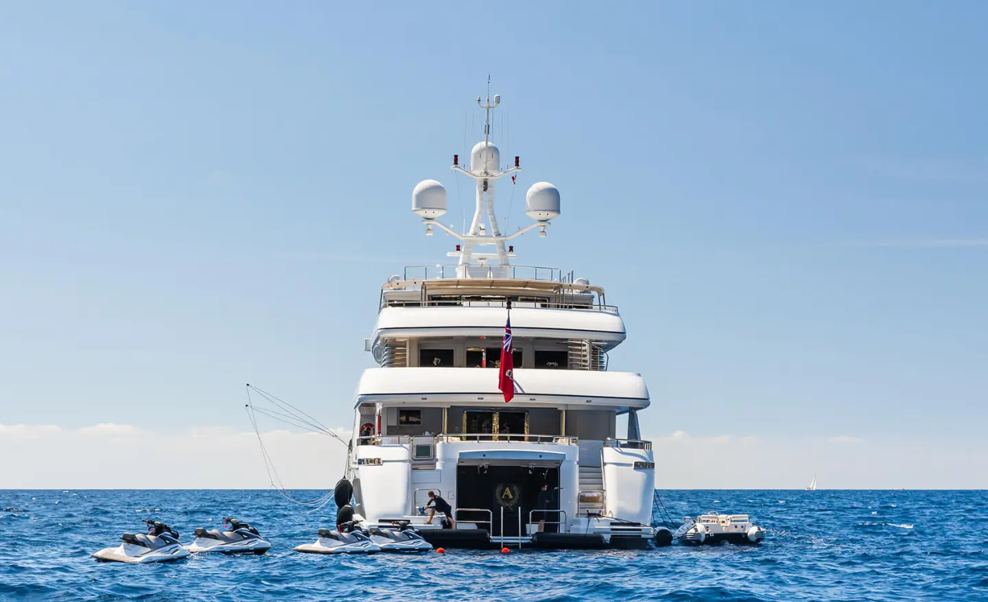 Apogee yacht docked, rear view on calm blue sea with clear sky
