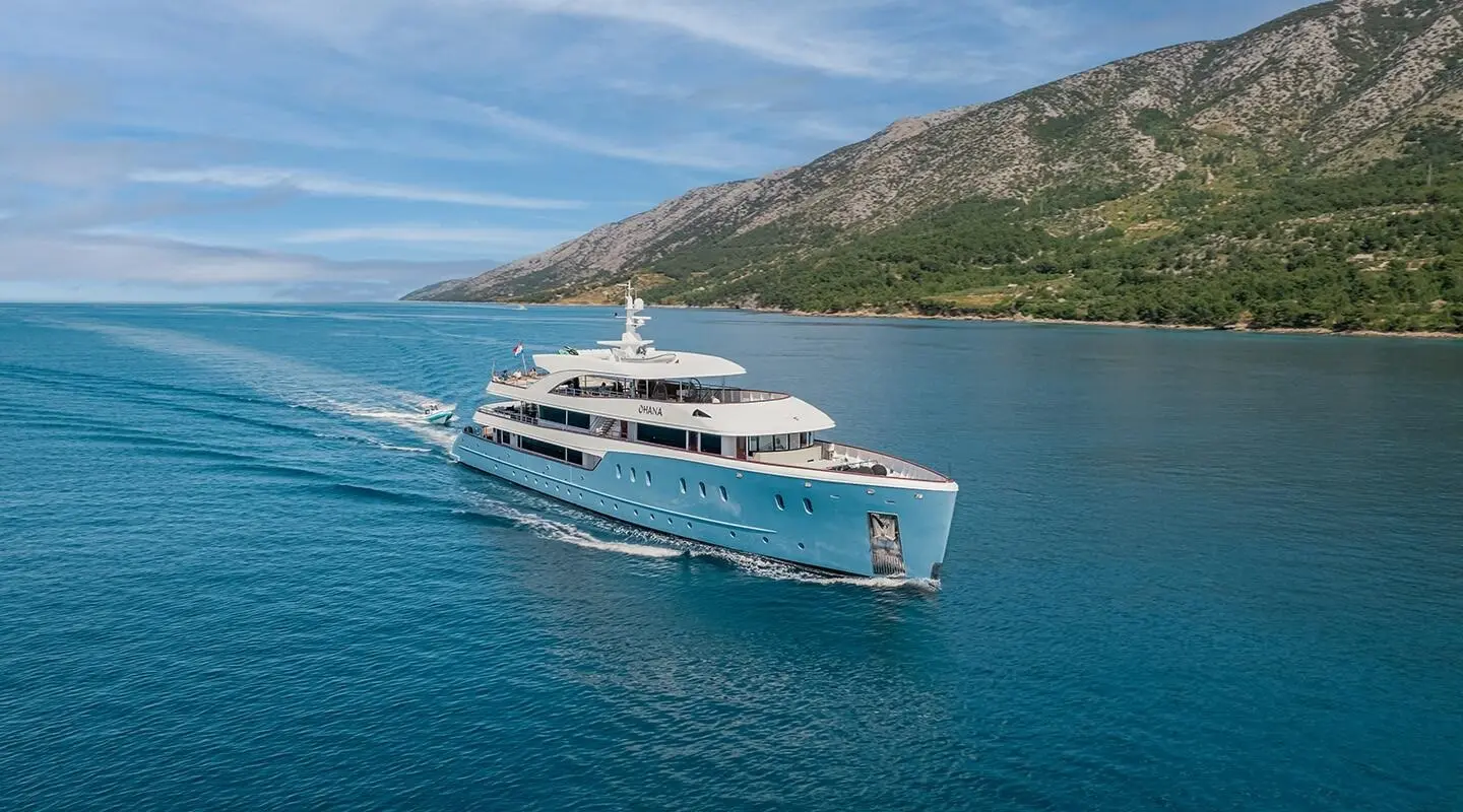 Ohana motor yacht anchored in clear blue water near rocky coastline