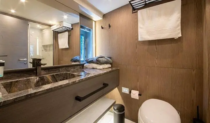 Master cabin with king bed, ensuite, wood tones, hanging towels, window view