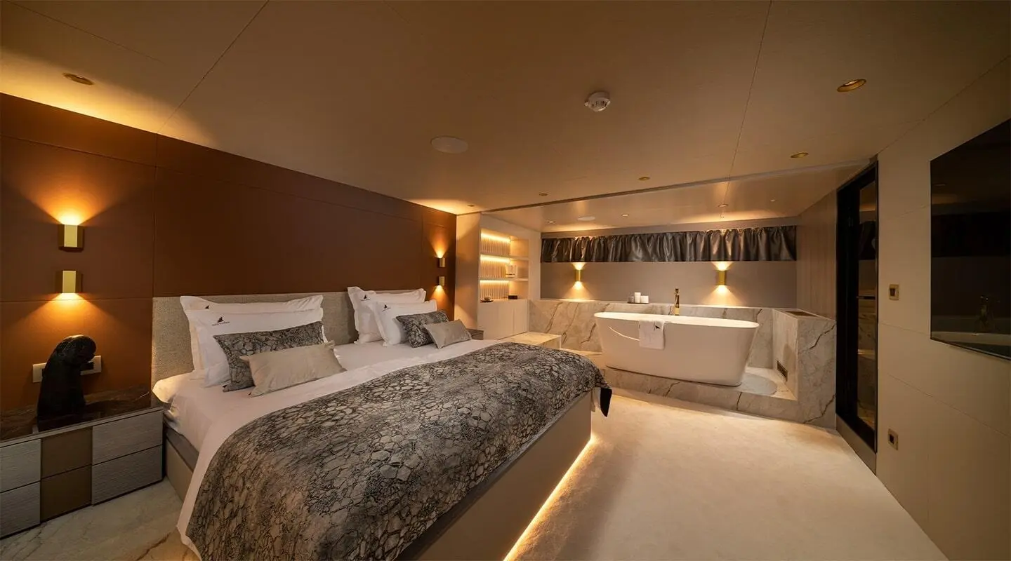 Nocturno yacht interior: luxurious bedroom with bed, warm lighting and seating area