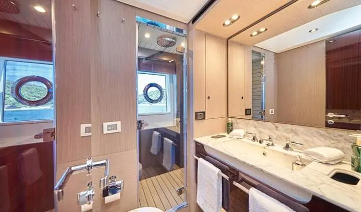 Master cabin with king bed, ensuite bathroom, wood cabinetry and porthole