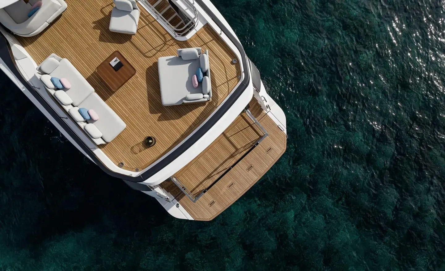 Aerial view of the yacht deck with teak seating area over clear water