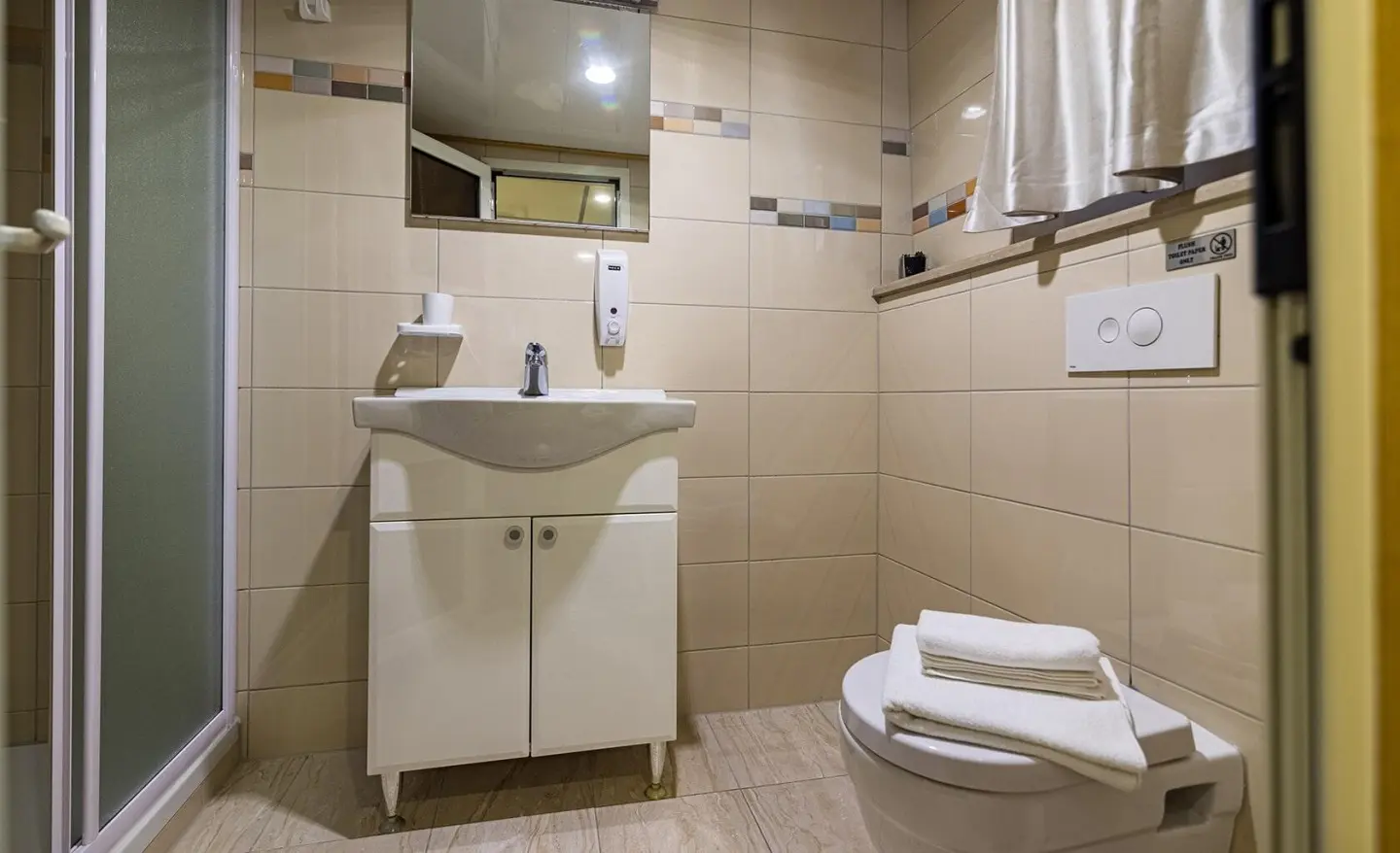Bathroom aboard Melody yacht with sink, mirror, and toilet in beige-tiled space