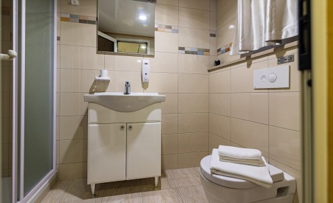 Bathroom of the Melody yacht, sink with cabinet, toilet with folded towels, shower enclosure on the left