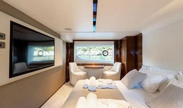 Yacht Vista cabin with king bed, stylish seating area, windows, and soft lighting