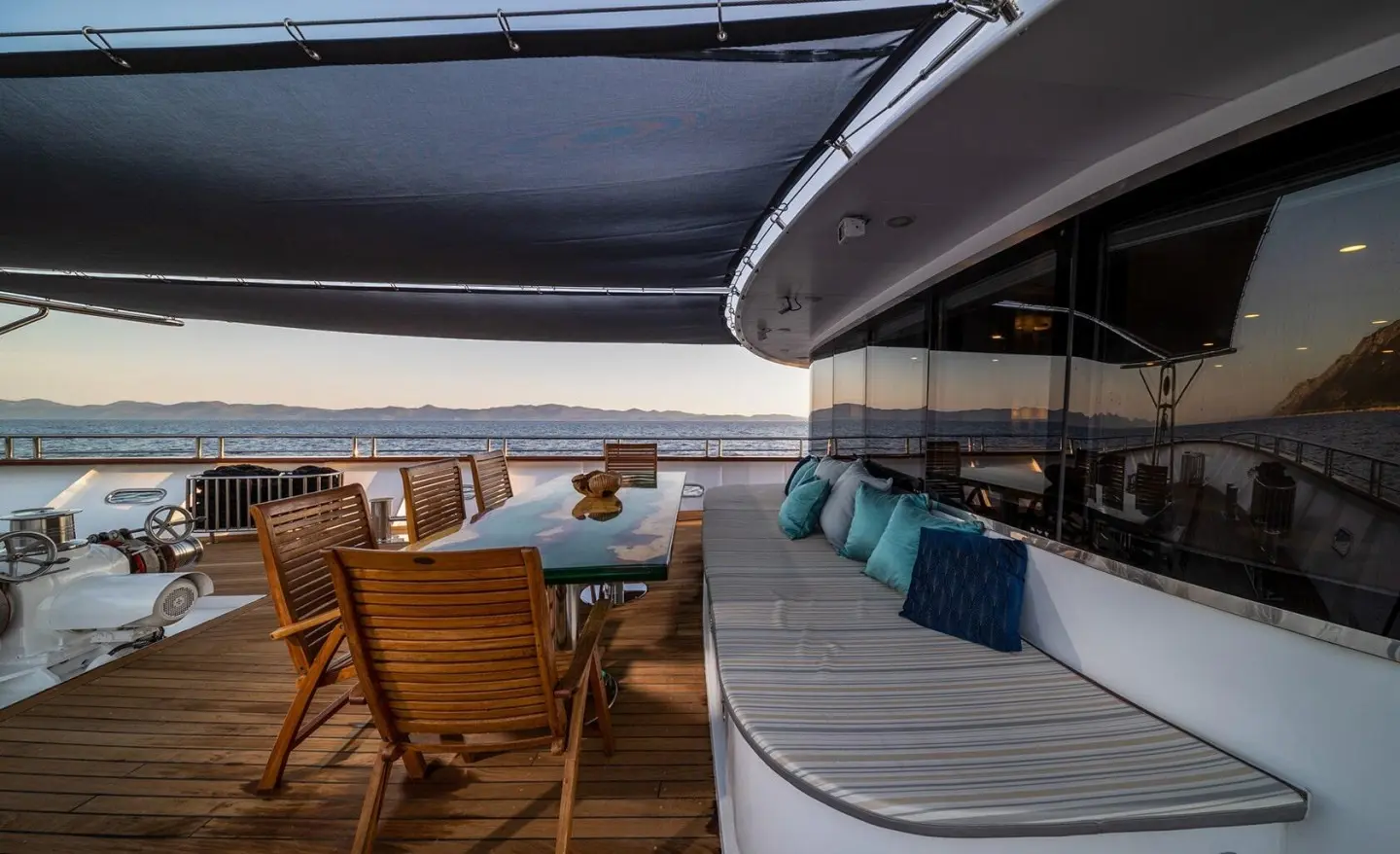 Luxurious yacht Olimp dining area with wooden table and seating on deck
