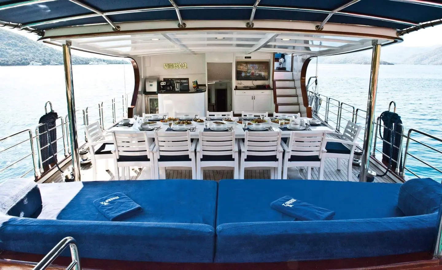 Maske 2 yacht exterior with blue seating and white deck at sunset dining area