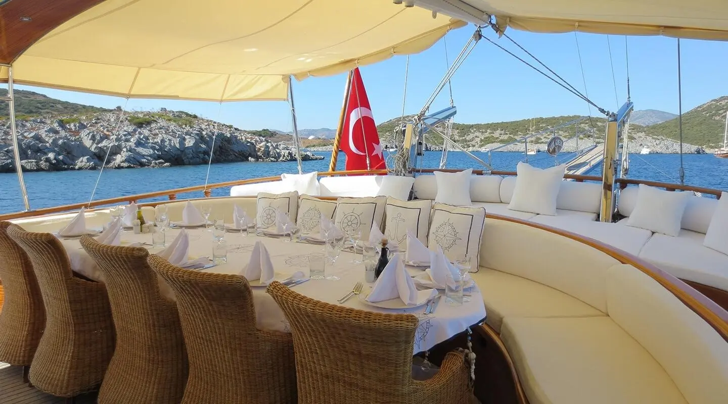 Kaya Guneri 4 yacht deck with seating, table set, sunny harbor view at sunset