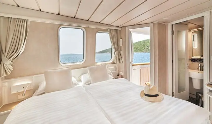 Luxurious yacht cabin with king bed, porthole windows, and ensuite hints