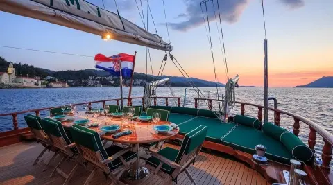 Carpe Diem 7 yacht deck at sunset with dining table set for guests