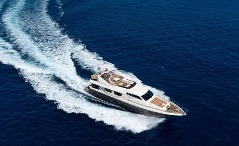 Luxury motor yacht Lady Natassa speeding across blue sea, wake visible