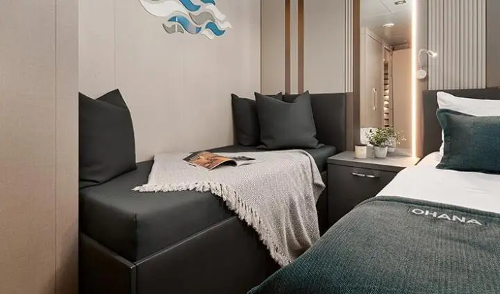 Ohana yacht cabin with dark sofa, cushions, and light curtains