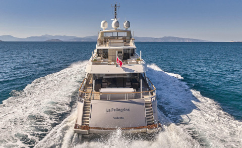 From the stern, the La Pellegrina 1 yacht with open deck seating and rear stairs visible on calm sea