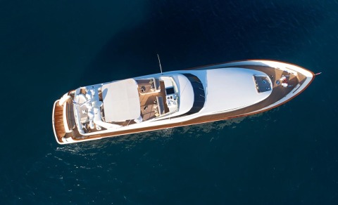 Aquila motor yacht seen from above in blue sea with white hull and wooden deck details