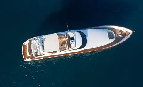 Aerial view of Aquila yacht cruising blue sea, white hull slicing water