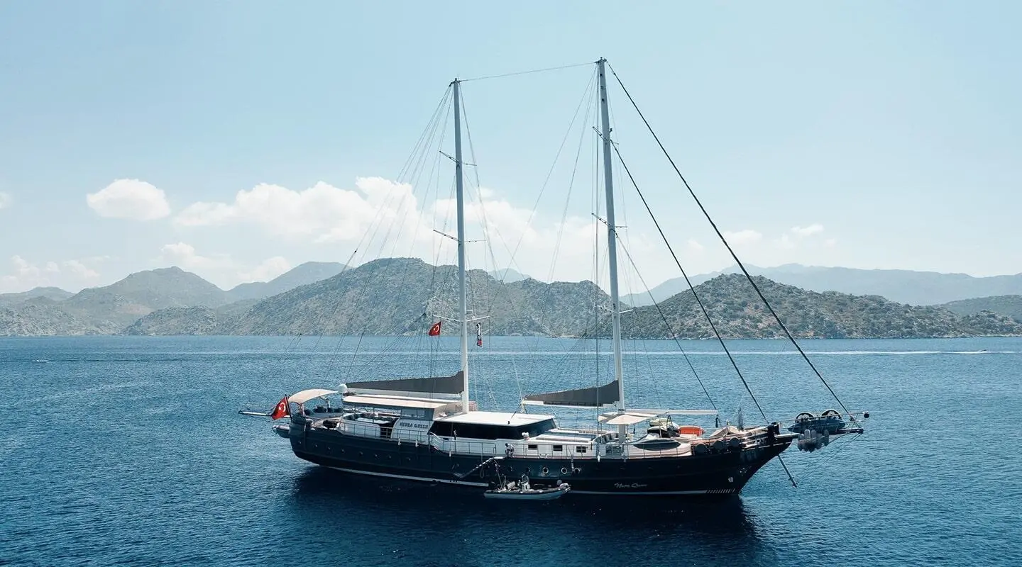 Sailing yacht on calm sea with distant rocky islands
