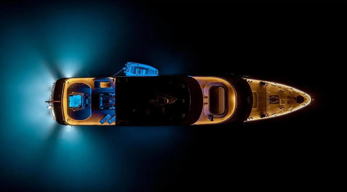 Top-down view of a luxury motor yacht named Freedom at night, illuminated hull sails