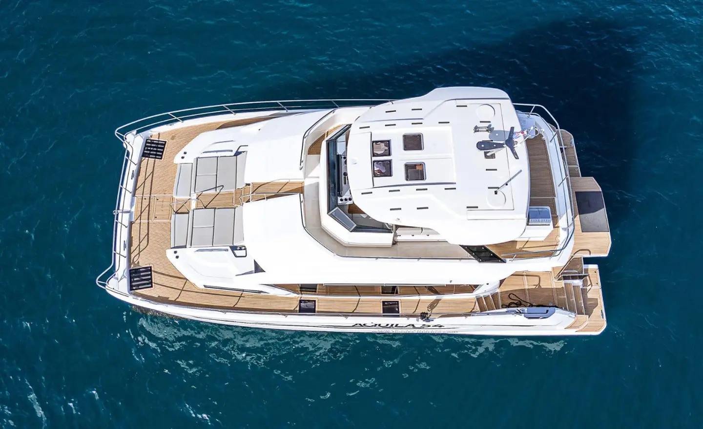 Top-down view of a white yacht named By My Side cruising blue sea