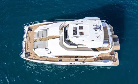 Top-down view of a white yacht named By My Side cruising blue sea