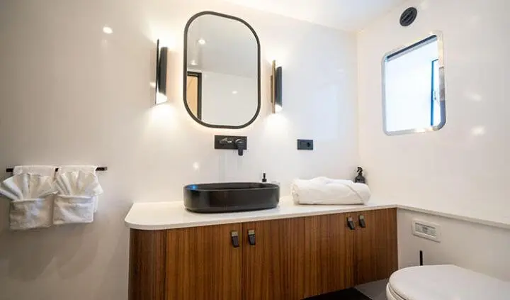 Master cabin with king bed, ensuite, wood bid vanity, round mirror, soft lighting