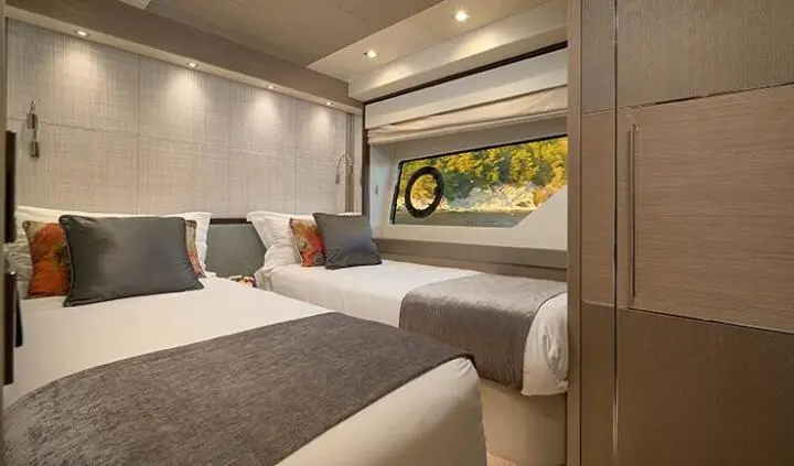 Twin bunk cabin on Hideaway yacht with bed, cushions, window view, warm wood tones