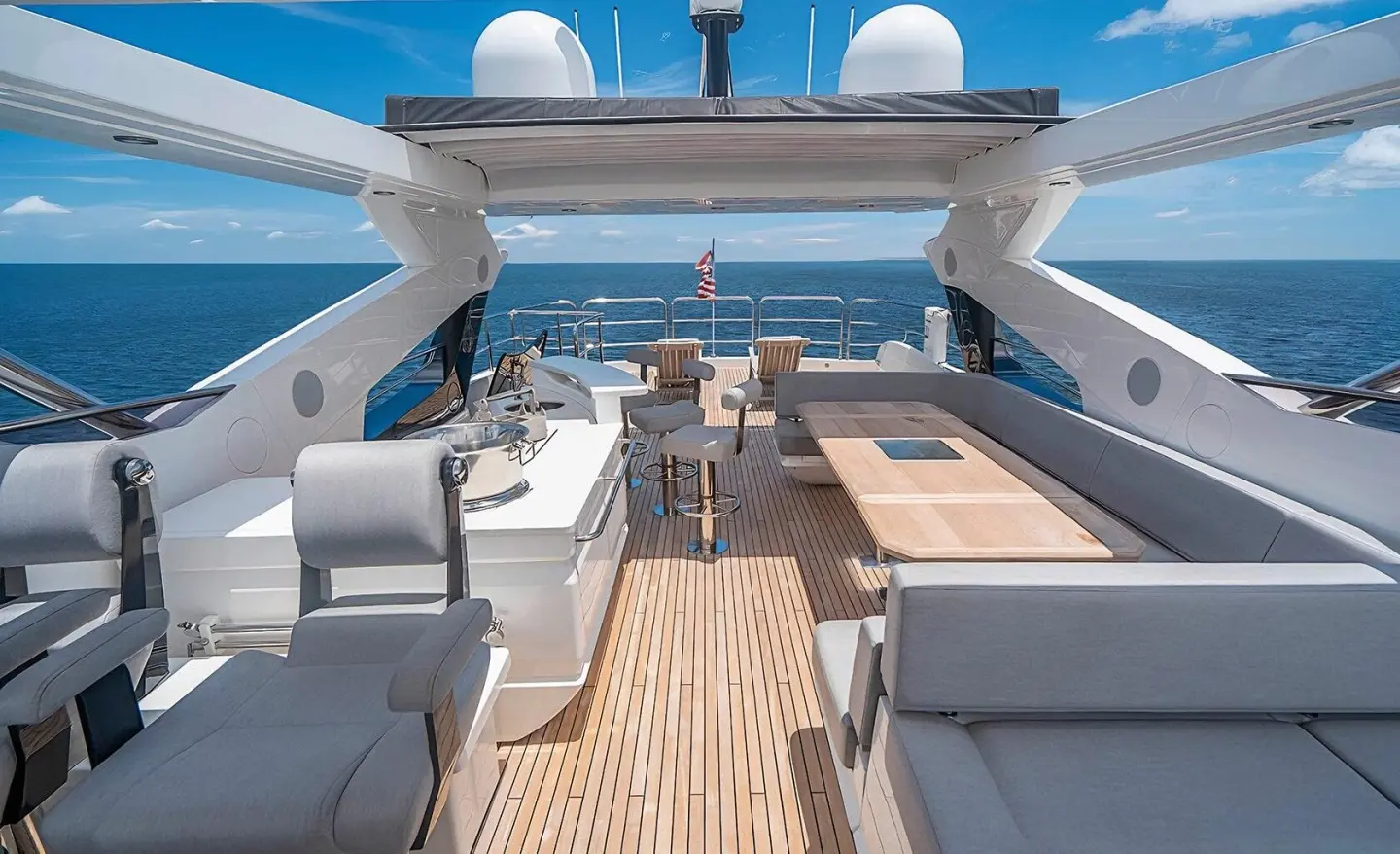 Quantum yacht deck with seating area, sun loungers, and polished wood planks at sunset