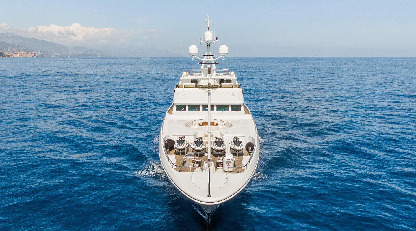 A luxury yacht named Apogee sails calm blue ocean, bow forward
