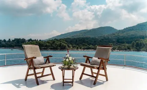 Cesarica yacht sailside deck with two chairs and small table overlooking blue sea