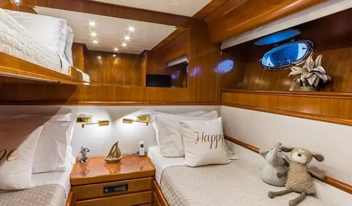 Amoraki yacht cabin with twin bunks, wood paneling, and porthole lighting