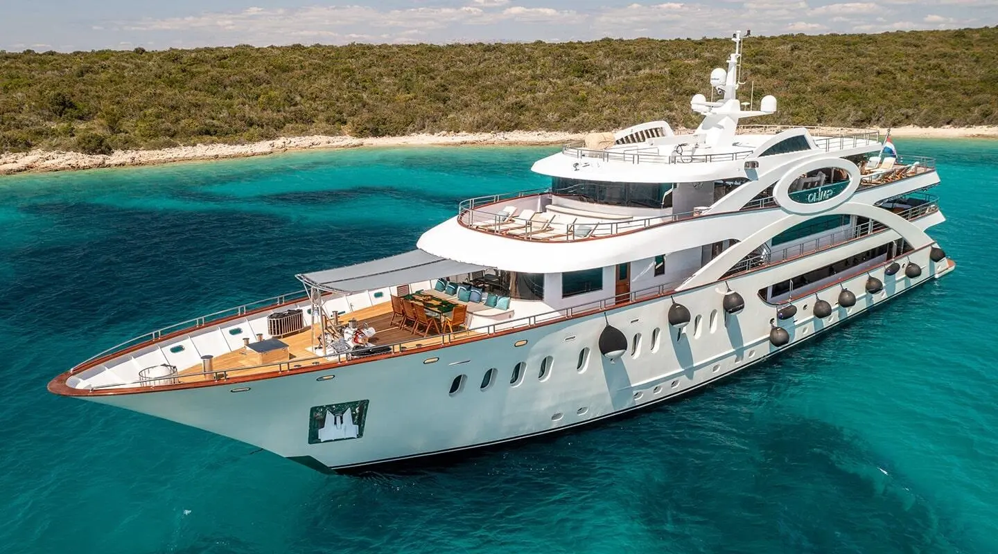 Olimp luxury yacht anchored in clear blue water with deck seating and sun loungers