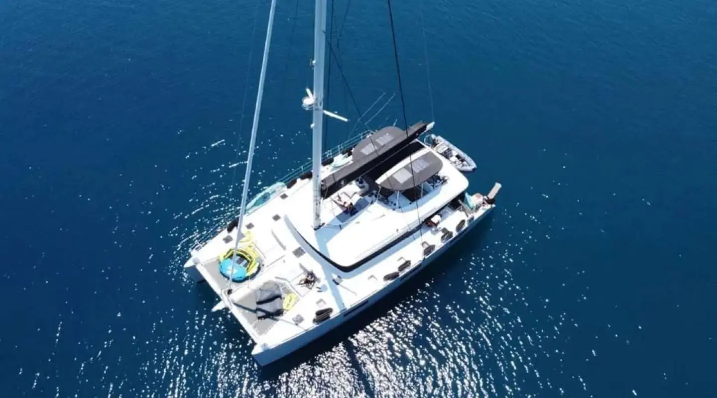 A sleek white sailing yacht named Atlantis anchored in calm blue water