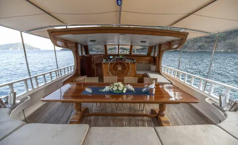 Kayhan 8 yacht deck with wooden helm, seating, and steering wheel at sunset