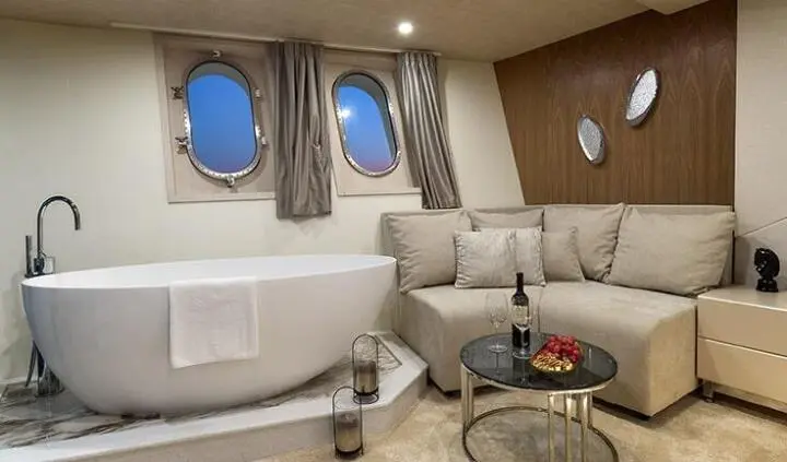 Luxurious yacht cabin with large beige sofa, wood accents, round windows