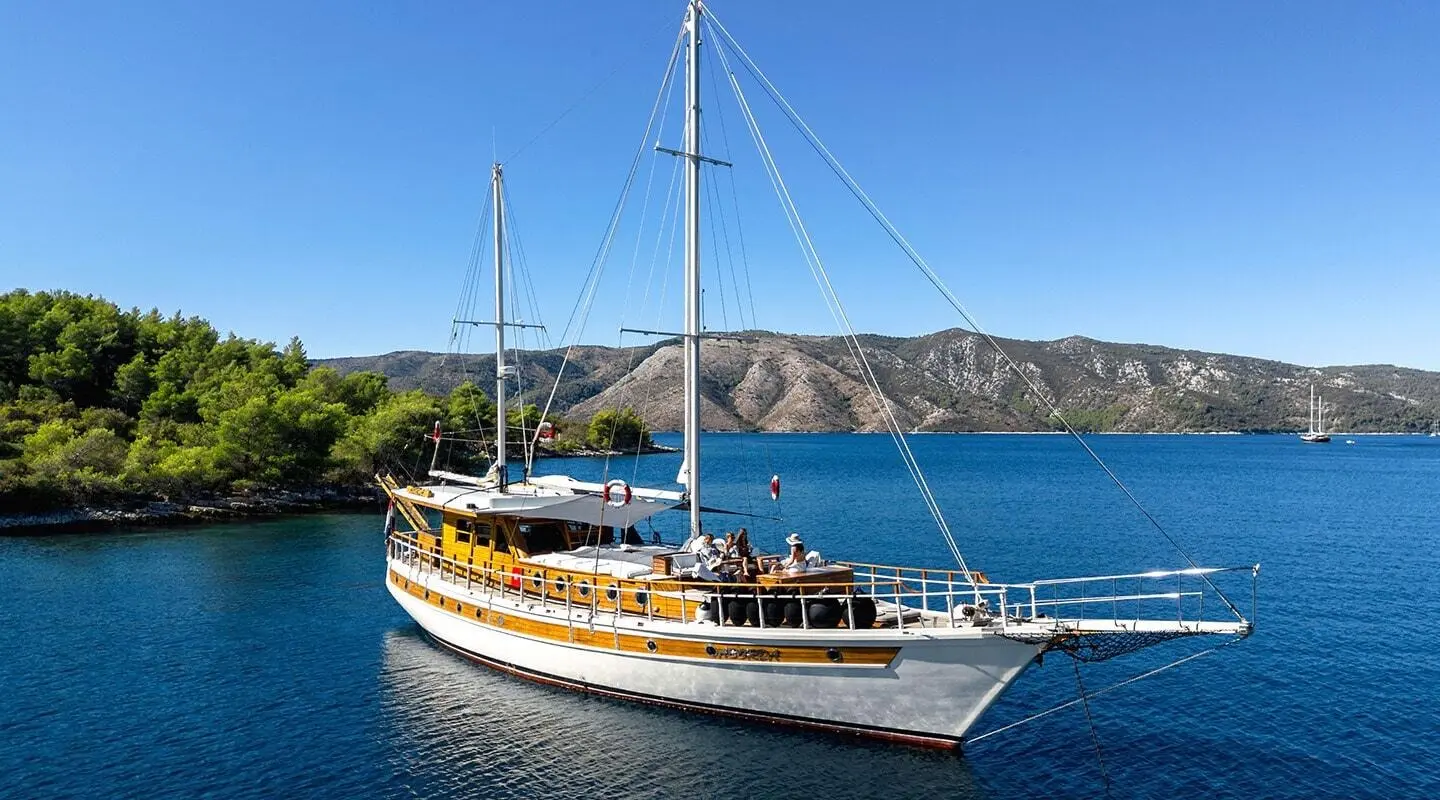 Wooden gulet sailboat with passengers moored in calm blue sea