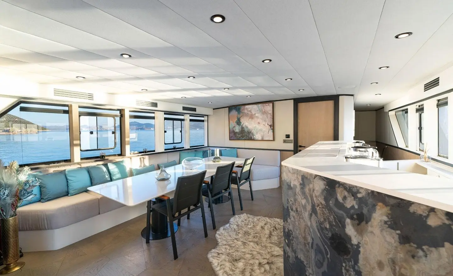 Calm Down yacht salon with seating, bar, and large windows, stylish interior